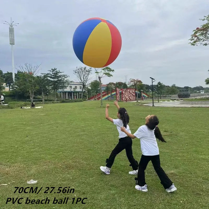Two people playing with a large colorful beach ball in an open field.