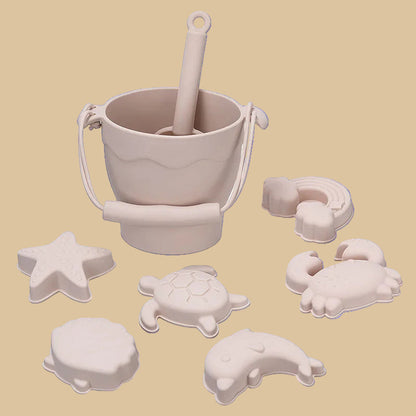 Beige sand pail and shovel with various beach-themed molds on a white background