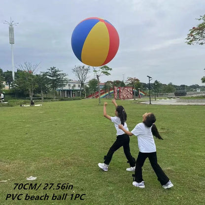 Two people playing with a large colorful beach ball in an open field.