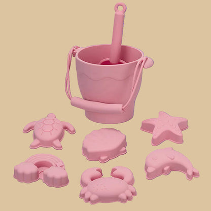 Pink sand toys including a bucket and various sea creature molds on a blue background